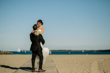Bräutigam hebt Braut am Strand