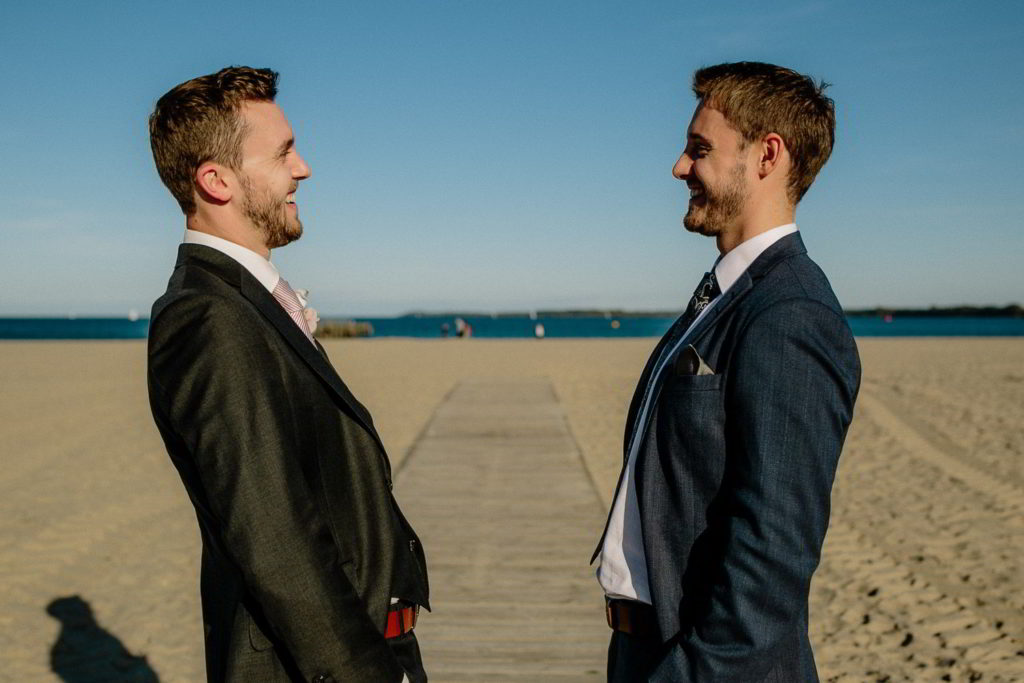 Bräutigam und Trauzeuge lachen am Strand