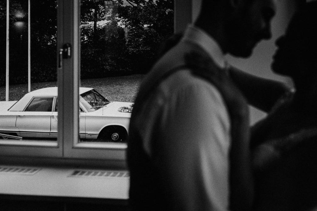 Brautpaar umarmt sich in Villa Rissen vor Oldtimer