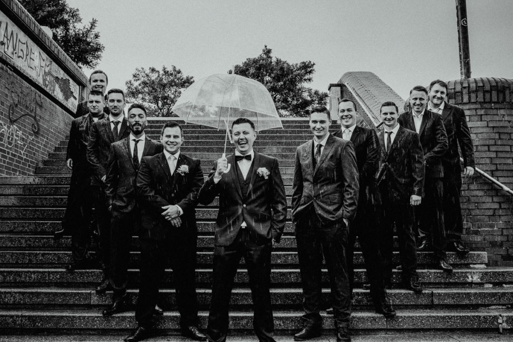 Bräutigam mit Regenschirm und Trauzeugen